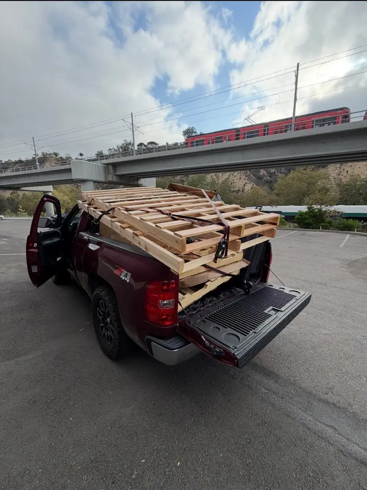 Stack of old wooden pallets strapped onto the back of the pickup